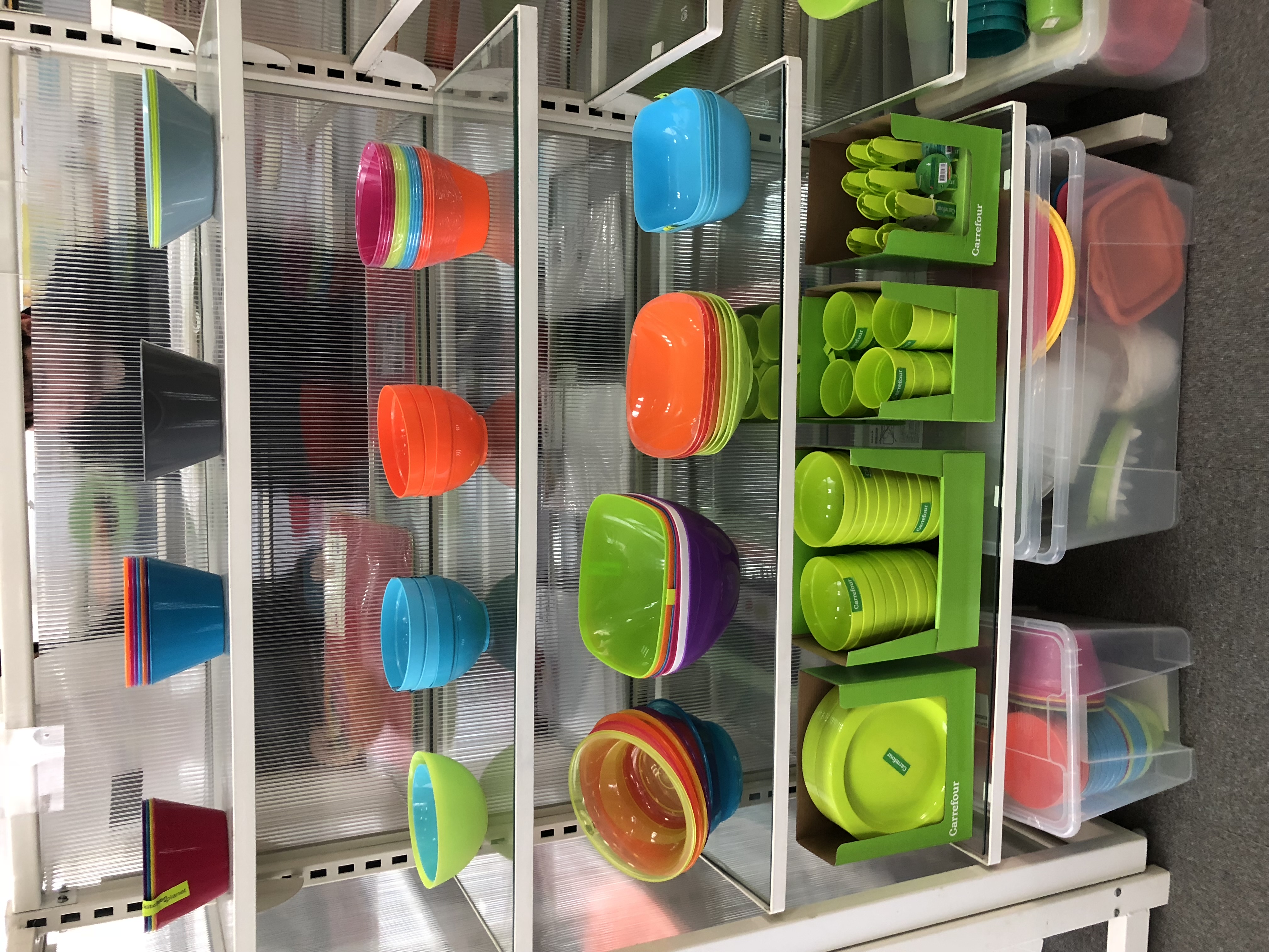 Buntes Plastikgeschirr im Regal – Mindestmengen und Verpackungseinheiten bestimmen die Kalkulation im Import