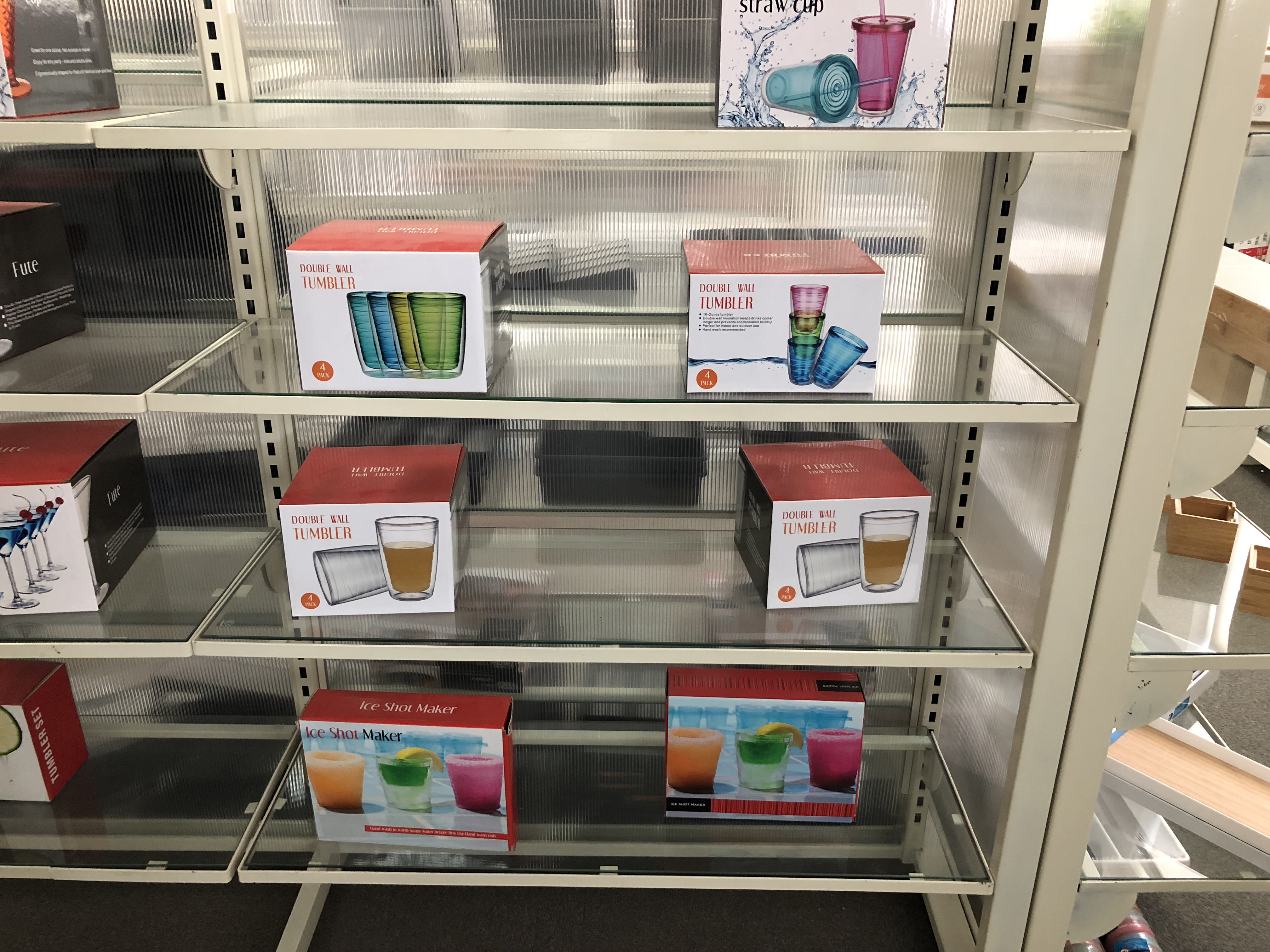 Verkaufsregal mit verpackten, wiederverwendbaren Trinkwaren-Sets: doppelwandige Tumbler in 4er-Boxen und wiederverwendbare Trinkbecher – Produktverpackung für nachhaltige Beschaffung im Einzelhandel